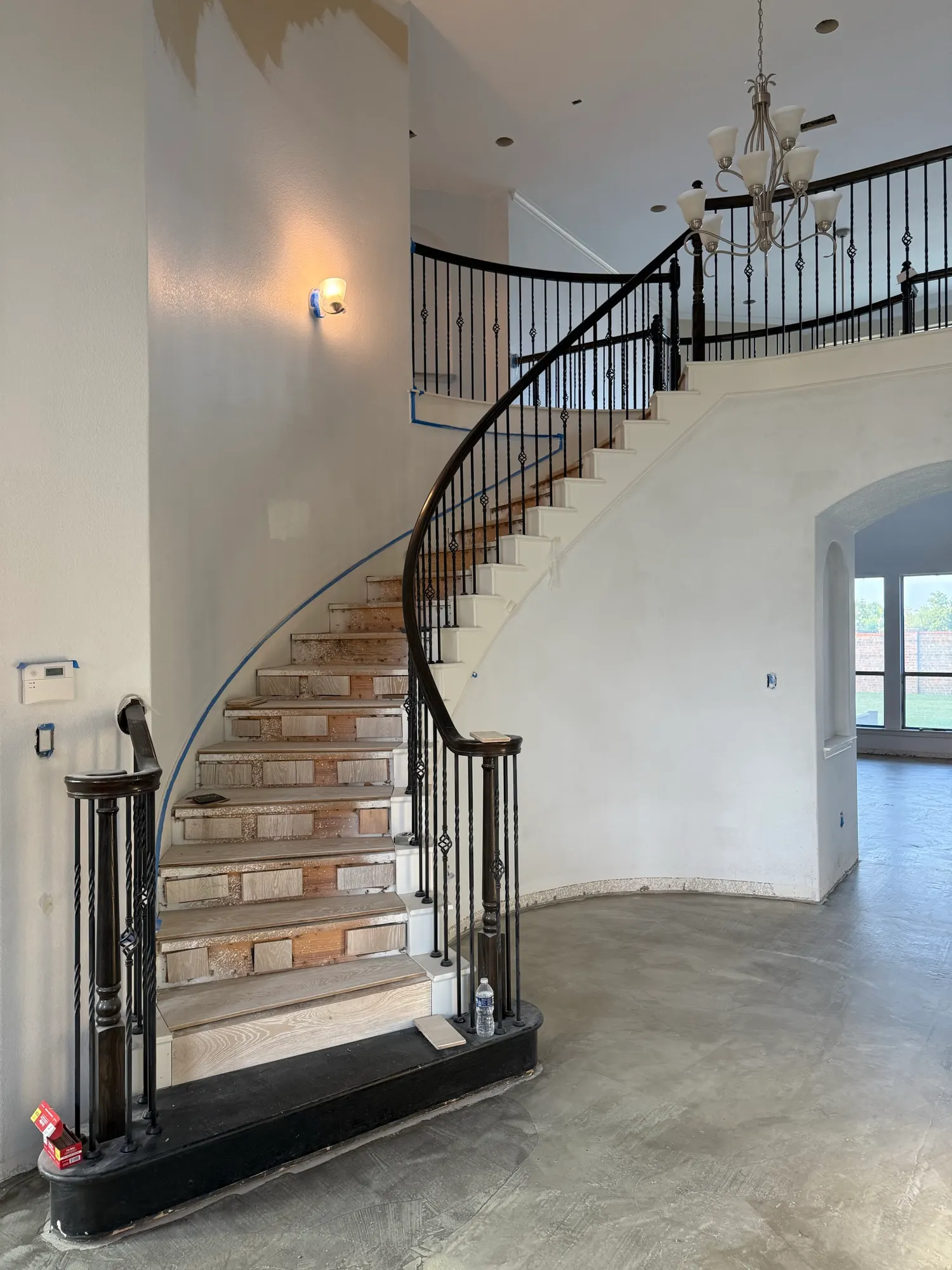 Before: curved staircase with the carpet pulled up and a bare concrete floor