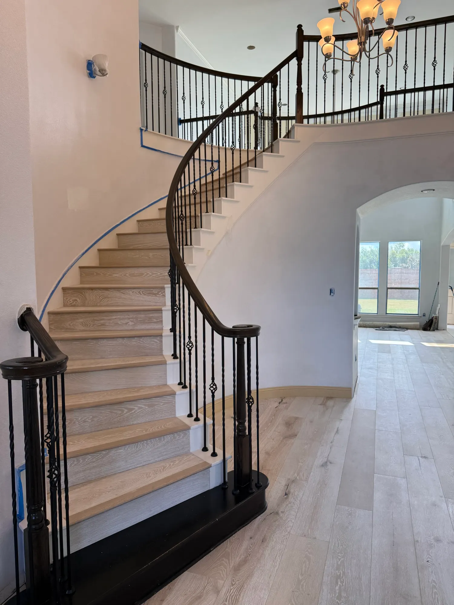 After: the same staircase with light oak treads, black risers and matching wide-plank wood floors