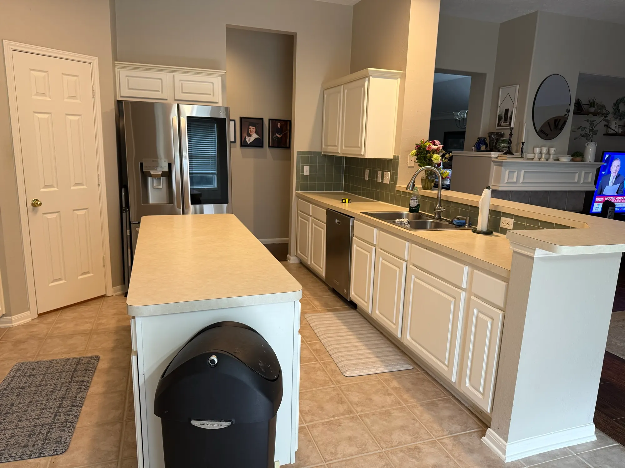 Before: builder-grade kitchen with white cabinets, a small laminate island and beige tile floors